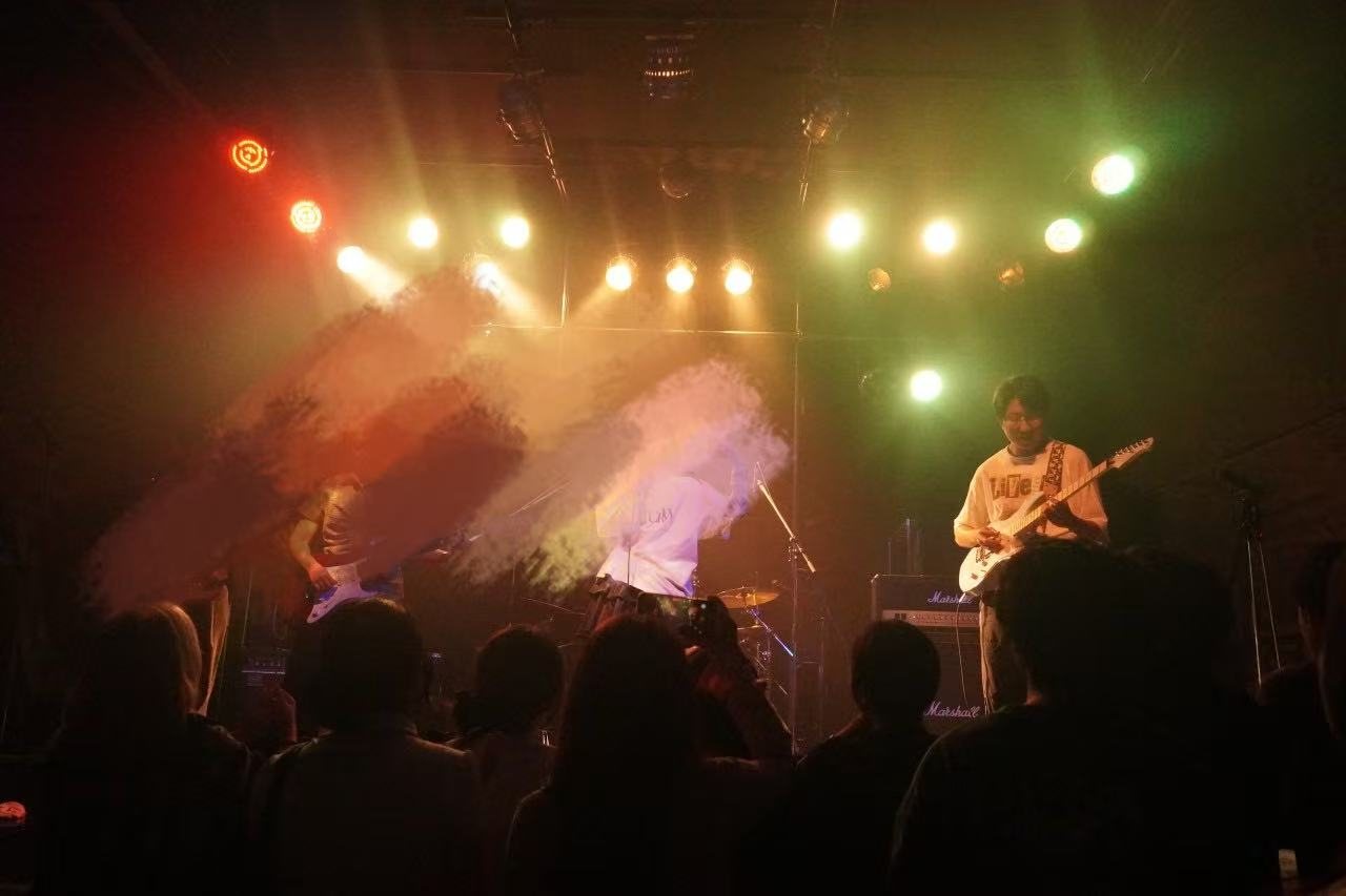 Zhaoyang Yuan performing electric guitar with a band at Kyoto TRUST live house